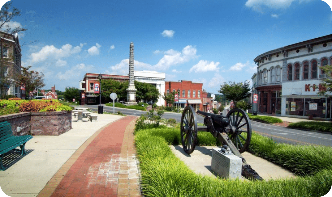 Downtown Chester street view showcasing historic brick storefronts, a sidewalk, and a historic cannon display on the right.